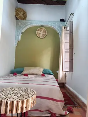 a bedroom with a bed with a table in it at Dar Le Monde in Marrakech