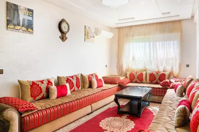 a living room with red couches and a clock on the wall at حي الشرف in Marrakech