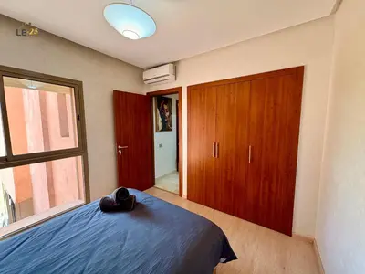 a bedroom with a bed with a hat on it at Appartement Prestigia Agate résidence avec piscine in Marrakech