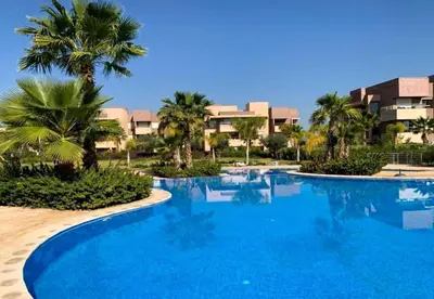 a large swimming pool with palm trees and buildings at Appartement Prestigia Agate résidence avec piscine in Marrakech