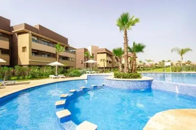 a large swimming pool with chairs and a building at Appartement Prestigia Agate résidence avec piscine in Marrakech