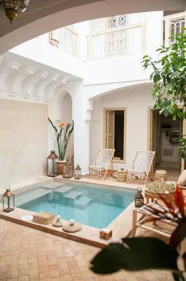 a swimming pool in a house with two chairs at Riad À l'ombre des Orangers in Marrakech
