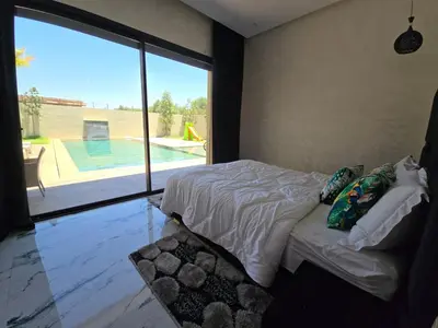 a bedroom with a bed with a view of a swimming pool at Villa echwitter in Marrakech