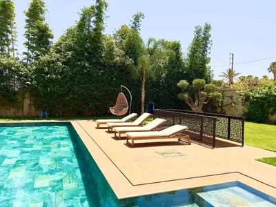 a group of lounge chairs next to a swimming pool at villa éden marrakech in Oulad Ikhia