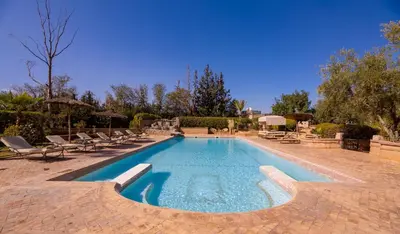 a large swimming pool with lounge chairs at Villa Ferme de Coco in El Caïd Omar