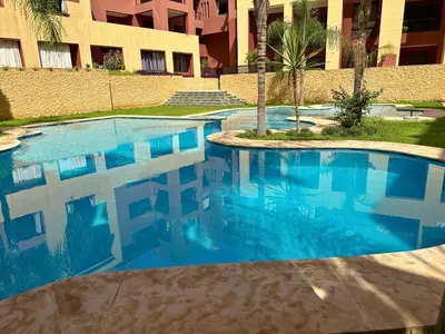 a blue swimming pool in front of a building at Somptueux Appartement avec Jacuzzi Privé Marrakech in Marrakech