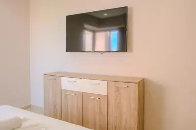 a television on a wall above a wooden cabinet at Luxury 2BD in Prestigia Jade with Pool and Golf View in Marrakech