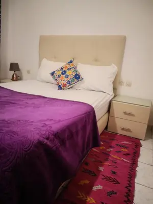 a bed with a purple blanket and pillows on it at big house with swiming pool in Marrakech