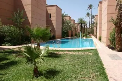 a swimming pool in front of a building with palm trees at big house with swiming pool in Marrakech