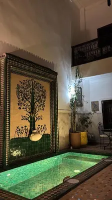 a swimming pool in a room with a painting on the wall at Riad Thycas in Marrakech
