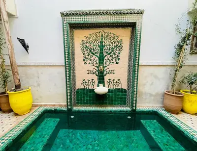 a pool in a house with a painting of a tree at Riad Thycas in Marrakech
