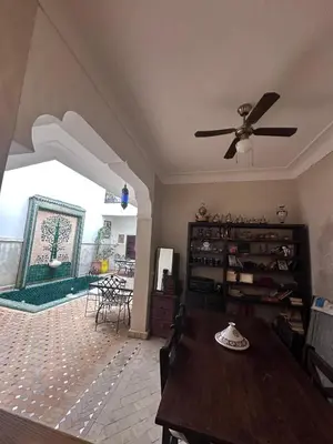 a living room with a ceiling fan and a table at Riad Thycas in Marrakech