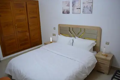 a bedroom with a large white bed and wooden cabinets at Pause Hivernal a Marrakech charme et confort in Marrakech