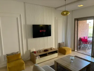 a living room with a tv on a wall at Beautiful residence with pools inMarrakech Golf City in Marrakech