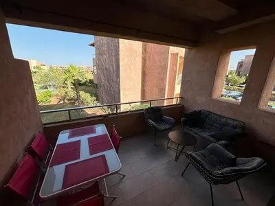 a balcony with chairs and a table and a couch at Beautiful residence with pools inMarrakech Golf City in Marrakech