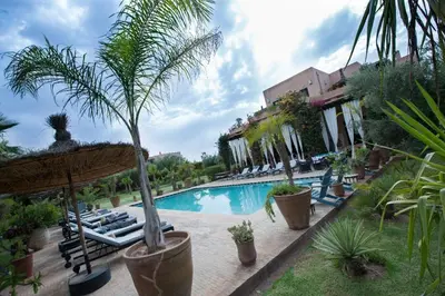 a resort swimming pool with lounge chairs and palm trees at Dar abie in Sraghna