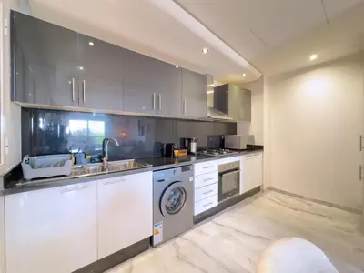a kitchen with white cabinets and a sink and a dishwasher at Charme Appt En Résidence Riad Garden Avec Piscine in Marrakech