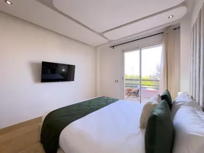 a bedroom with a bed and a tv and a window at Charme Appt En Résidence Riad Garden Avec Piscine in Marrakech