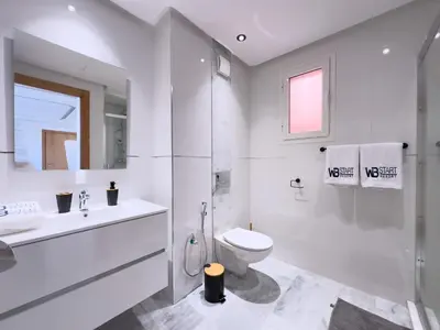 a white bathroom with a toilet and a sink at Charme Appt En Résidence Riad Garden Avec Piscine in Marrakech