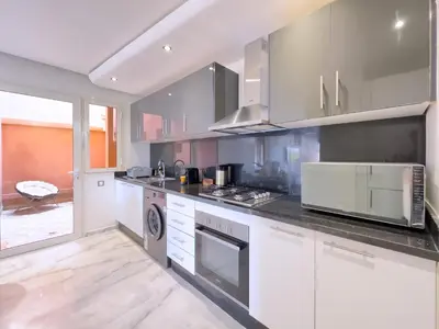 a kitchen with stainless steel appliances and a large window at Charme Appt En Résidence Riad Garden Avec Piscine in Marrakech