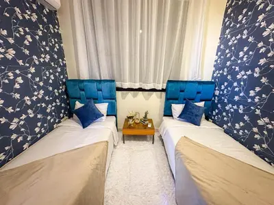 two twin beds in a room with blue chairs at Amazing Apartment Center city in Marrakech
