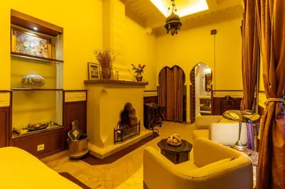 a living room with yellow walls and a fireplace at Riad Habouba in Marrakech