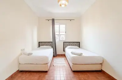 two beds in a room with white walls at Golden Palm 2 in Marrakech