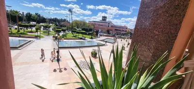 a group of people walking around a pool in a park at La Plaza cœur de Gueliz in Marrakech