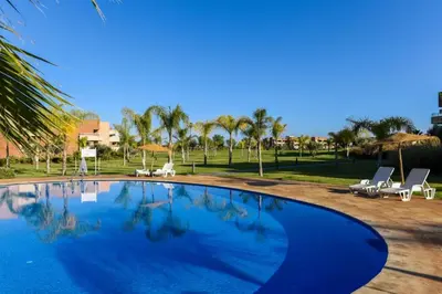 a large swimming pool with lounge chairs and umbrellas at Prestigious residence marrakech with optical fiber in Marrakech