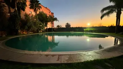 a large swimming pool with a sunset in the background at Mms in Marrakech
