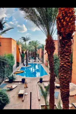 a swimming pool in a resort with palm trees at Raid lkaram in Marrakech