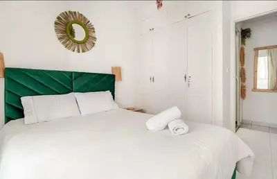 a bedroom with a large white bed with a green headboard at Confort et style en pleins centre ville in Marrakech