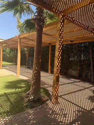 a wooden pergola with a palm tree in a yard at Villa Famous 4 chambres in Marrakech