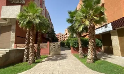 a group of palm trees in front of a building at Appartement raffiné avec piscine au centre ville in Marrakech