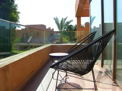 a black chair sitting on a balcony with a table at Timeless Villa at Golf course with private pool in Marrakech
