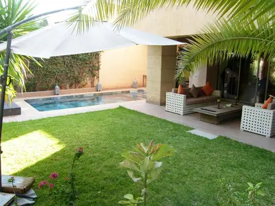a backyard with a swimming pool and an umbrella at Timeless Villa at Golf course with private pool in Marrakech