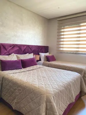 a bedroom with two beds with purple pillows and a window at Appartement cosy à Marrakech in Marrakech