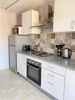 a kitchen with white cabinets and a stove and refrigerator at Appartement cosy à Marrakech in Marrakech