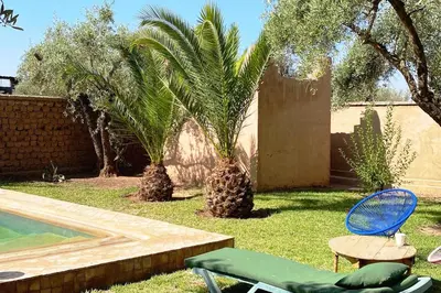 a yard with two palm trees and a pool at DAR TITRIT Charming house with garden and pool in Akhatar