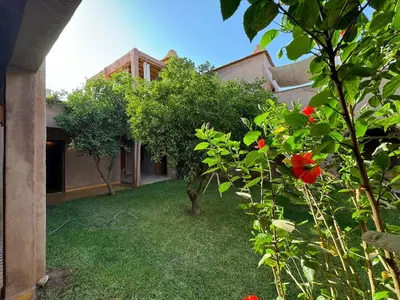 a house with a yard with red flowers and trees at DAR EL KERMA Traditional Rustic House in Châba