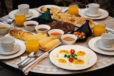 a table with a breakfast of eggs and bread at RIAD Dar ZOMOROD in Marrakech