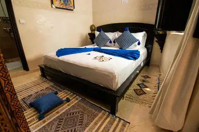 a bedroom with a bed with blue and white pillows at RIAD Dar ZOMOROD in Marrakech