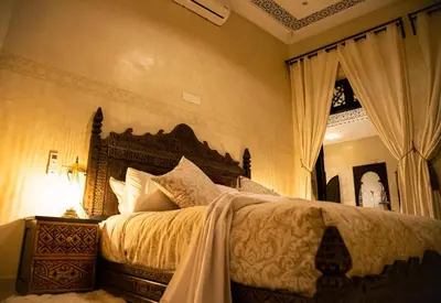 a bedroom with a large bed and a mirror at RIAD Dar ZOMOROD in Marrakech