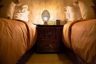 a bedroom with two beds and a lamp on a night stand at RIAD Dar ZOMOROD in Marrakech