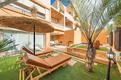 a patio with a chair and an umbrella and a palm tree at Your Haven of Peace with Private Jacuzzi in Marrakech
