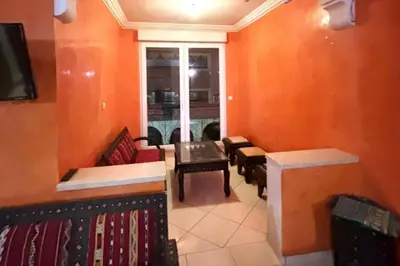 a living room with orange walls and a table and chairs at Charme & Confort -2 Chambres-Wifi-Azar in Marrakech