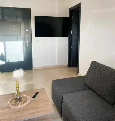 a living room with a couch and a television at Appartement 1 chambre - Superbe Terrasse & Vue Panoramique - Semlalia in Marrakech