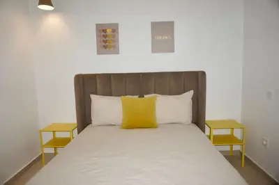 a bed with a wooden headboard with yellow pillows at Appartement moderne rénové in Marrakech