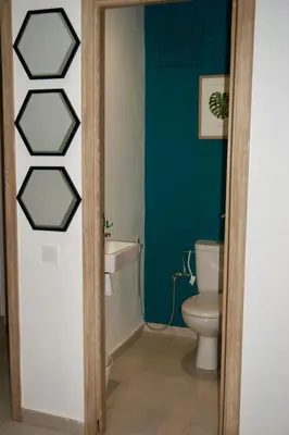 a bathroom with a toilet and a green wall at Appartement moderne rénové in Marrakech