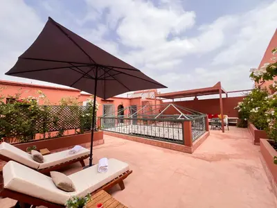 a patio with a large black umbrella and benches at Riad Kech One & Spa in Marrakech